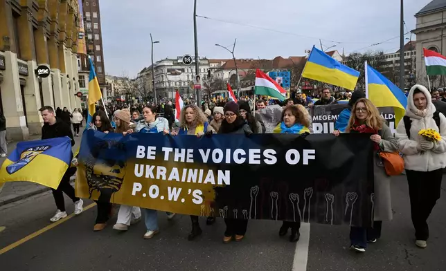 People walk with Ukrainian flags to the Russian Embassy during a solidarity march in support of Ukraine in Budapest, Sunday, Feb. 22, 2026, two days ahead of the fourth anniversary of Russia's full-scale invasion of Ukraine. (Noemi Bruzak/MTI via AP)