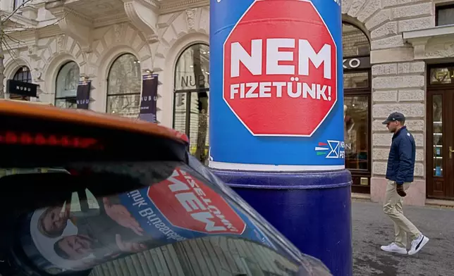 A man passes a billboard that shows an AI-generated image of Ukrainian President Volodymyr Zelenskyy flanked by European officials and reads: "We Don't Pay," in Budapest, Hungary, Monday Feb. 23, 2026. (AP Photo/Bela Szandelszky)