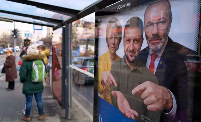 A billboard showing an AI-generated image of Ukrainian President Volodymyr Zelenskyy, center, flanked by European officials is displayed at a bus stop in Budapest, Hungary, Monday, Feb. 23, 2026. (AP Photo/Bela Szandelszky)