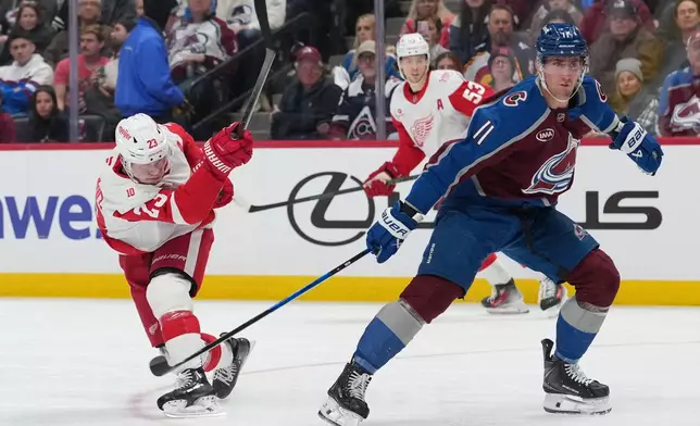 Detroit Red Wings left wing Lucas Raymond, left, shoots the puck past Colorado Avalanche center Brock Nelson, right, in the second period of an NHL hockey game Monday, Feb. 2, 2026, in Denver. (AP Photo/David Zalubowski)