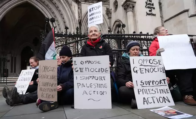 Protesters hold placards outside the High Court, in London, Friday Feb. 13, 2026, where Judges Victoria Sharp, Jonathan Swift and Karen Steyn have ruled in favour of Palestine Action's co-founder Huda Ammori's challenge over the ban of the organisation as a terror group. (Jonathan Brady/PA via AP)