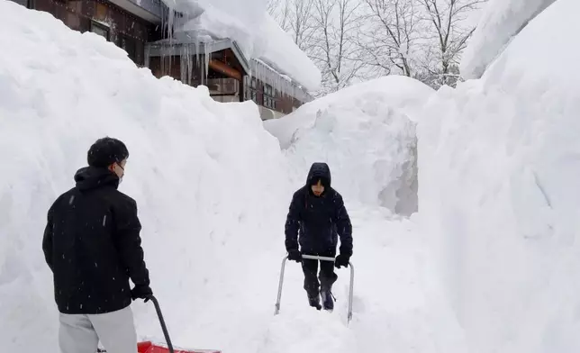 People clear snow near houses in Aomori, northern Japan, Monday, Feb. 2, 2026. (Kyodo News via AP)