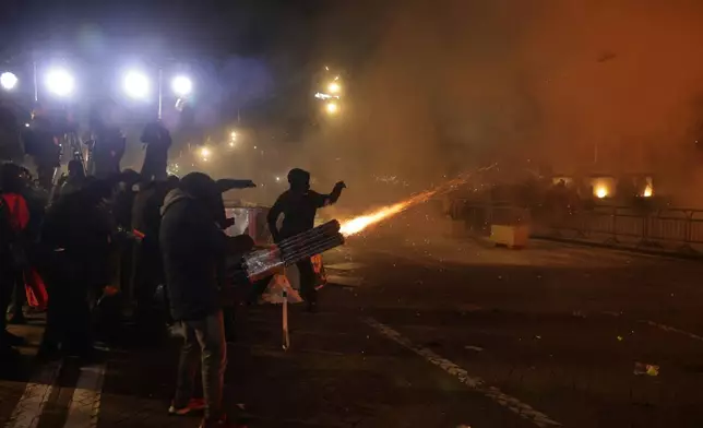 Hooded youth protesters throw flares and fireworks during an anti-government rally outside Prime Minister's office over corruption scandals and broader political issues, in Tirana, Albania, Tuesday, Feb. 10, 2026. (AP Photo/Hameraldi Agolli)