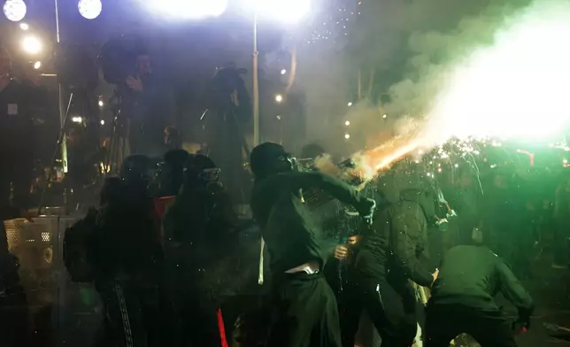 Hooded youth protesters throw flares and fireworks during an anti-government rally outside Prime Minister's office over corruption scandals and broader political issues, in Tirana, Albania, Tuesday, Feb. 10, 2026. (AP Photo/Hameraldi Agolli)