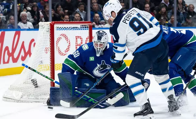Vancouver Canucks goaltender Nikita Tolopilo (60) stops Winnipeg Jets' Cole Perfetti (91) during the second period of an NHL hockey game in Vancouver, B.C., on Wednesday, Feb. 25, 2026. (Ethan Cairns/The Canadian Press via AP)