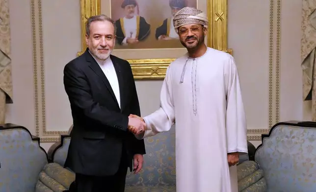 In this photo released by the Iranian Foreign Ministry, Iranian Foreign Minister Abbas Araghchi, left, shakes hands with his Omani counterpart Sayyid Badr Albusaidi during their meeting prior to Iran and the U.S. negotiations, in Muscat, Oman, Friday, Feb. 6, 2026. (Iranian Foreign Ministry via AP)