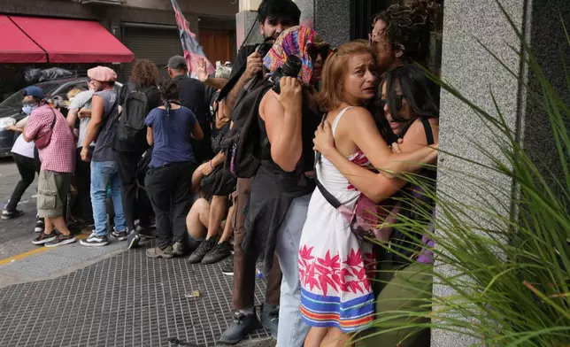 People take cover as police and protesters clash during a march by trade unions and opposition groups against a labor reform bill proposed by President Javier Milei's government in Buenos Aires, Argentina, Wednesday, Feb. 11, 2026. (AP Photo/Rodrigo Abd)