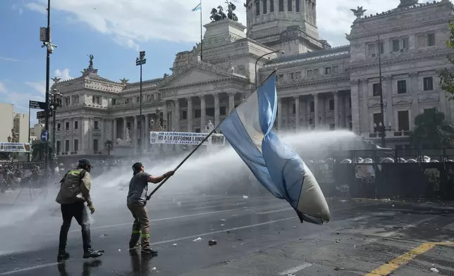 A protester waves a flag during a march by unions and opposition supporters against a labor reform bill proposed by President Javier Milei's government outside Congress in Buenos Aires, Argentina, Wednesday, Feb. 11, 2026. (AP Photo/Rodrigo Abd)