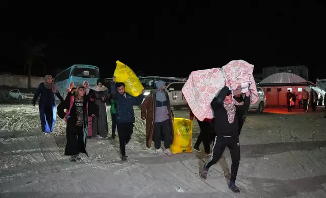 Palestinians carry the belongings of relatives arriving in Gaza from Egypt following the long-awaited reopening of the Rafah border crossing, in Khan Younis, southern Gaza Strip, early Thursday, Feb. 5, 2026. (AP Photo/Abdel Kareem Hana)