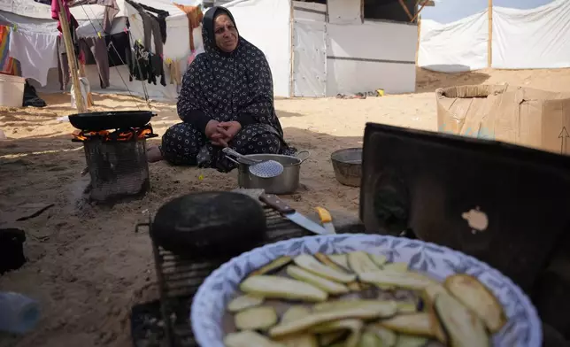 Siham Omran, 54, recently returned from Egypt after completing medical treatment, cooks food over a fire beside her tent in Khan Younis, in the southern Gaza Strip, Saturday, Feb. 7, 2026. (AP Photo/Abdel Kareem Hana)