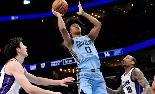 Memphis Grizzlies forward Jaylen Wells (0) shoots between Sacramento Kings center Maxime Raynaud, left, and guard DeMar DeRozan (10) in the first half of an NBA basketball game Monday, Feb. 23, 2026, in Memphis, Tenn. (AP Photo/Brandon Dill)