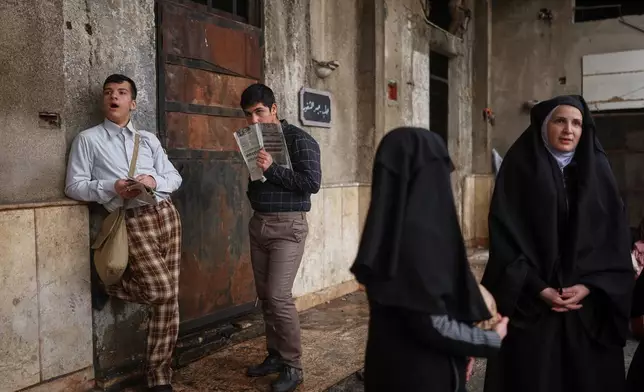 Extras stand by as a television crew films an episode of the TV series "Al-Souriyoun al-Aada" ("The Syrian Enemies"), based on a novel of the same name that was banned under Bashar Assad, along a transformed street in central Aleppo, Syria, Friday, Feb. 13, 2026. (AP Photo/Ghaith Alsayed)