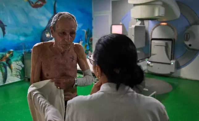 Jorge Elias speaks with the doctor after his radiotherapy session at the National Institute of Oncology and Radiology in Havana, Cuba, Friday, Feb. 20, 2026. (AP Photo/Ramon Espinosa)
