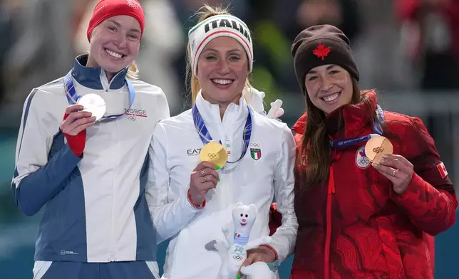 Francesca Lollobrigida of Italy, center and gold medal celebrates with Ragne Wiklund of Norway, left and silver medal, and Valerie Maltais of Canada, right and bronze medal, on the podium of the women's 3,000 meters speedskating race at the 2026 Winter Olympics, in Milan, Italy, Saturday, Feb. 7, 2026. (AP Photo/Christophe Ena)