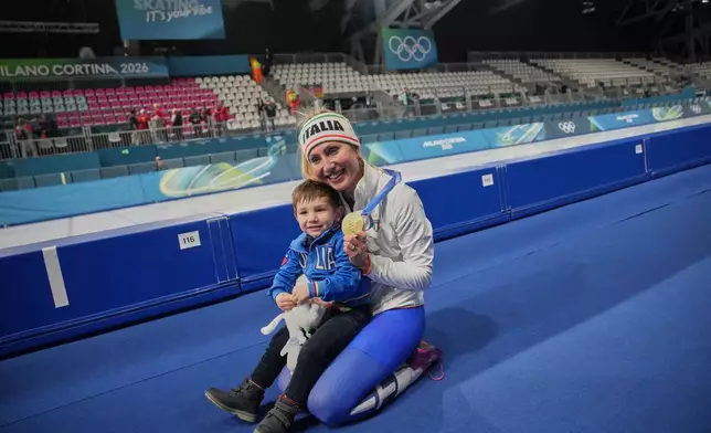 Francesca Lollobrigida of Italy celebrates with her son Tommaso after winning the gold medal in the women's 3,000 meters speedskating race at the 2026 Winter Olympics, in Milan, Italy, Saturday, Feb. 7, 2026.. (AP Photo/Christophe Ena)