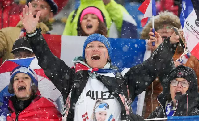 Fans of France celebrate after Julia Simon, of France, won silver and Oceane Michelon, of France, won gold in the women's 12.5-kilometer mass start biathlon race at the 2026 Winter Olympics in Anterselva, Italy, Saturday, Feb. 21, 2026. (AP Photo/Mosa'ab Elshamy)