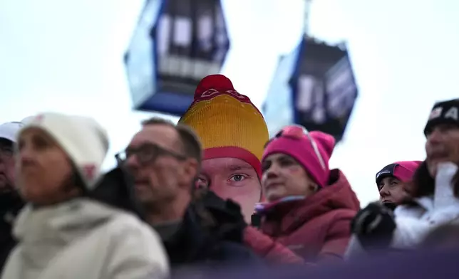 People hold a giant portrait of Germany's Max Langenhan in the finish area during a men's single luge run at the 2026 Winter Olympics, in Cortina d'Ampezzo, Italy, Sunday, Feb. 8, 2026. (AP Photo/Alessandra Tarantino)