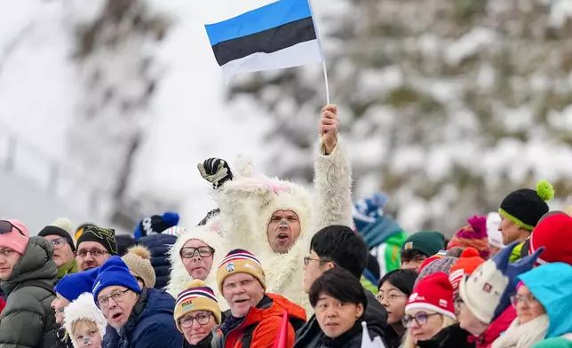 A fan waves a flag of Estonia during the ski jumping of the Nordic Combined Individual Gundersen Normal Hill/10km competition at the 2026 Winter Olympics, in Predazzo, Italy, Wednesday, Feb. 11, 2026. (AP Photo/Matthias Schrader)