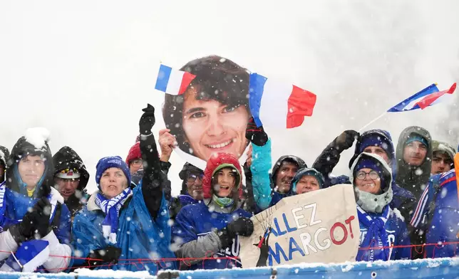 French fans hold a picture of competitor Margot Ravinel as they cheer during a ski mountaineering women's sprint semifinal, at the 2026 Winter Olympics, in Bormio, Italy, Thursday, Feb. 19, 2026. (AP Photo/Rebecca Blackwell)