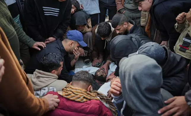 Palestinians mourn over the body of Hamas militant Ahmed Al-Bayouk, who was killed in an Israeli military strike, during his funeral at Nasser Hospital in Khan Younis, Gaza Sunday, Feb. 15, 2026. (AP Photo/Abdel Kareem Hana)