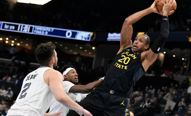 Golden State Warriors center Al Horford (20) handles the ball against Memphis Grizzlies guard Ty Jerome (2) and forward Olivier-Maxence Prosper in the first half of an NBA basketball game, Wednesday, Feb. 25, 2026, in Memphis, Tenn. (AP Photo/Brandon Dill)