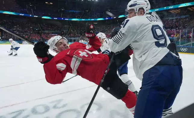 France's Floran Douay, right, checks Switzerland's Dean Kukan during a preliminary round match of men's ice hockey between Switzerland and France at the 2026 Winter Olympics, in Milan, Italy, Thursday, Feb. 12, 2026. (AP Photo/Carolyn Kaster)