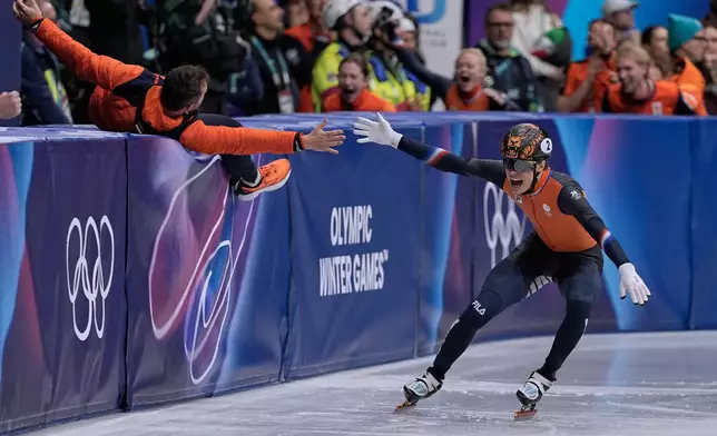 Jens van 't Wout of the Netherlands slaps hands with a coach after winning gold during the short track speed skating men's 1000m at the 2026 Winter Olympics, in Milan, Italy, Thursday, Feb. 12, 2026. (AP Photo/Ashley Landis)