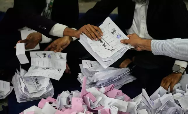 A Bangladeshi polling official handing over ballots shortly after the voting of national parliamentary election ended at a polling station in Dhaka, Bangladesh, Thursday, Feb. 12, 2026. (AP Photo/Anupam Nath)