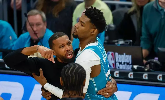 Charlotte Hornets forward Brandon Miller, right, holds back Hornets head coach Charles Lee, left, who yells at an official during the second half of an NBA basketball game against the Detroit Pistons in Charlotte, N.C., Monday, Feb. 9, 2026. Lee was ejected from the game. (AP Photo/Nell Redmond)