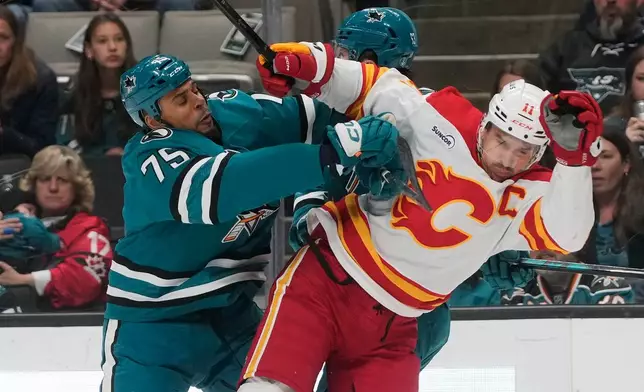 San Jose Sharks right wing Ryan Reaves (75) hits Calgary Flames center Mikael Backlund (11) during the first period of an NHL hockey game in San Jose, Calif., Thursday, Feb. 26, 2026. (AP Photo/Jeff Chiu)