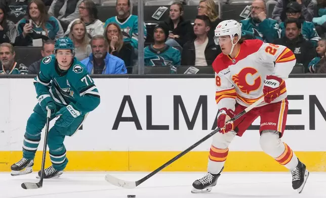 Calgary Flames defenseman Zach Whitecloud, right, skates with the puck against San Jose Sharks center Macklin Celebrini (71) during the first period of an NHL hockey game in San Jose, Calif., Thursday, Feb. 26, 2026. (AP Photo/Jeff Chiu)