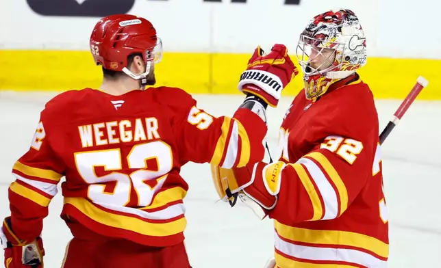 Calgary Flames goalie Dustin Wolf, right, is congratulated by MacKenzie Weegar after defeating the San Jose Sharks in an NHL hockey game in Calgary, Saturday, Jan. 31, 2026. (Larry MacDougal/The Canadian Press via AP)