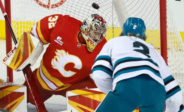 San Jose Sharks' Will Smith (2) scores on Calgary Flames goalie Dustin Wolf during the first period of an NHL hockey games in Calgary, Saturday, Jan. 31, 2026. (Larry MacDougal/The Canadian Press via AP)