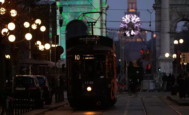 A traditional vintage trams travel on rails through a downtown street near to the Peace Arch, with a view of the Olympics cauldron in the background, ahead of the 2026 Winter Olympics, in Milan, Italy, Saturday, Jan. 31, 2026. (AP Photo/Luca Bruno)