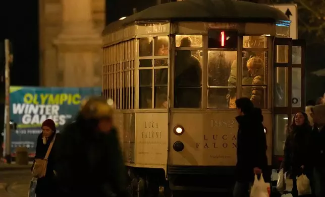 A traditional vintage tram waits for passengers at a stop near to a Milan Cortina Winter Olympics banner, in Milan, Italy, Saturday, Jan. 10, 2026. (AP Photo/Luca Bruno)