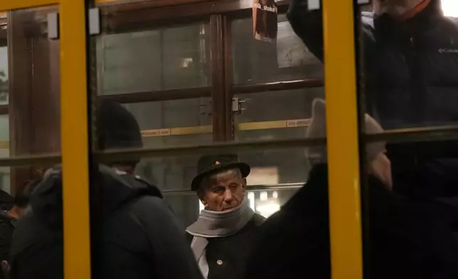 People travel in a traditional vintage tram on rails through a downtown street, in Milan, Italy, Saturday, Nov. 29, 2025. (AP Photo/Luca Bruno)