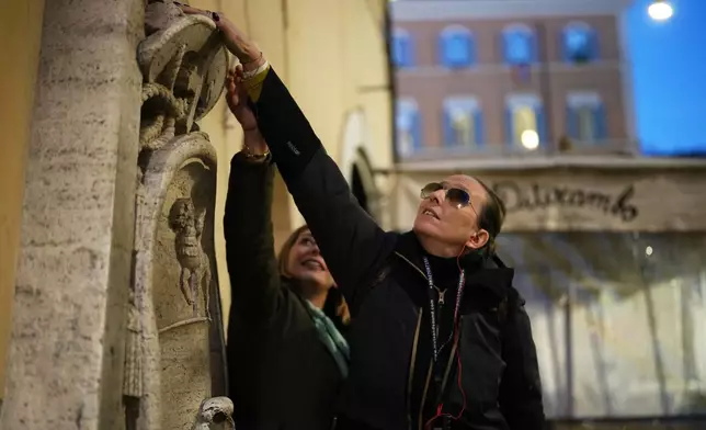 Elena Dominici, who is blind, touches the Cancelleria fountain during an inclusive art tour in downtown Rome, Nov. 29, 2025. (AP Photo/Alessandra Tarantino)