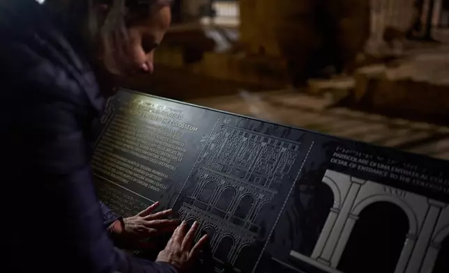 Michela Marcato, who is blind, runs her fingers over a tactile panel during a visit to the Colosseum in Rome, Dec. 17, 2025. (AP Photo/Alessandra Tarantino)