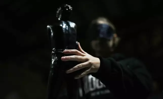 A blindfolded student of an art high school touches a piece in the pavilion of contemporary art during a project on tactile experience at the Omero Tactile Museum in Ancona, Italy, Friday, Jan. 16, 2026. (AP Photo/Alessandra Tarantino)