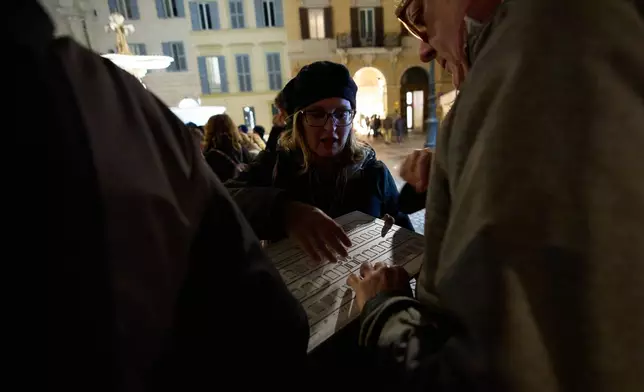 Daria Portale, a guide with the Radici Association, uses a tactile panel so Enrico Sulli, right, who is blind, can experience the architecture of Palazzo Farnese during an inclusive art tour in downtown Rome, Nov. 29, 2025. (AP Photo/Alessandra Tarantino)