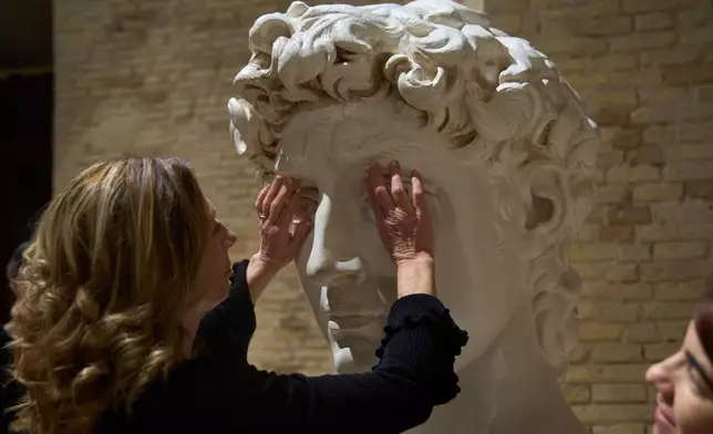 Stefania Terre, who is blind, touches a life-size reproduction of the head of Michelangelo's David during a visit to the Omero Tactile Museum in Ancona, Italy, Thursday, Jan. 15, 2026. (AP Photo/Alessandra Tarantino)