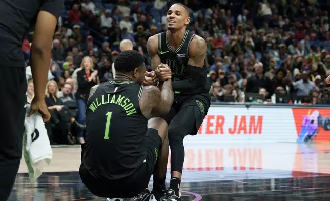New Orleans Pelicans guard Dejounte Murray (5) helps up forward Zion Williamson (1) during the second half of an NBA basketball game against the Golden State Warriors in New Orleans, Tuesday, Feb. 24, 2026. (AP Photo/Matthew Hinton)