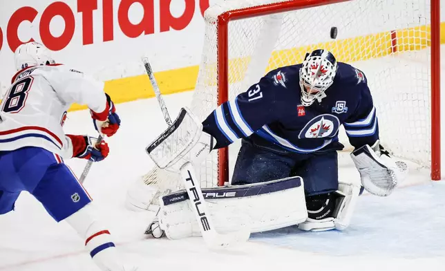 Montreal Canadiens' Lane Hutson (48) scores on Winnipeg Jets goaltender Connor Hellebuyck (37) during the second period of an NHL game in Winnipeg, Wednesday, Feb. 4, 2026. (John Woods/The Canadian Press via AP)