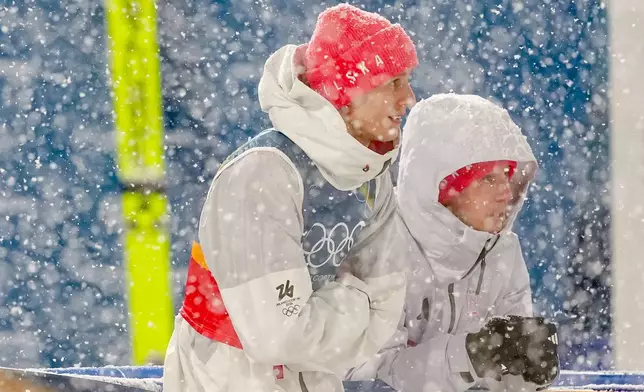 Pawel Wasek, left, and Kamil Stoch, both of Poland, wait while a snowfall interrupts the final round jump of the ski jumping men's super team competition at the 2026 Winter Olympics, in Predazzo, Italy, Monday, Feb. 16, 2026. (AP Photo/Matthias Schrader)