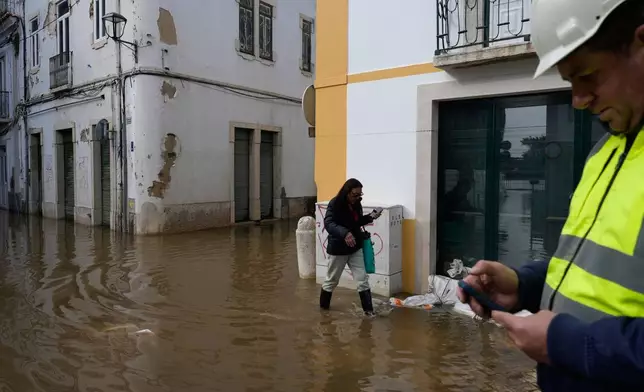 Residents walk through a flooded street after the Sado River overflowed following heavy rains in Alcácer do Sal, southern Portugal, Friday, Feb. 6, 2026. (AP Photo/Ana Brigida)