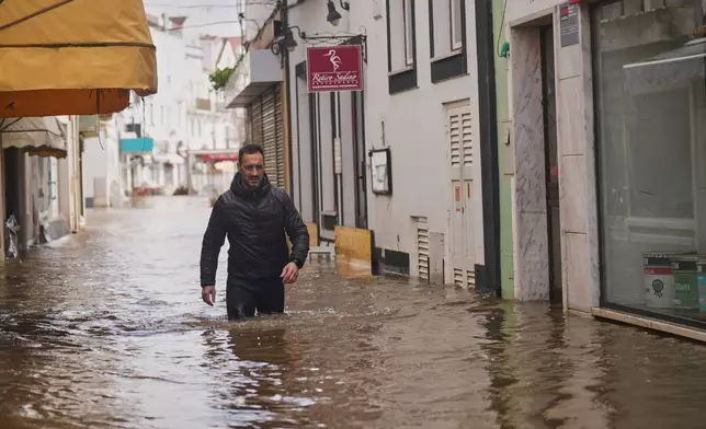 A residents walks along a flooded street after the Sado River overflowed following heavy rains in Alcácer do Sal, southern Portugal, Friday, Feb. 6, 2026. (AP Photo/Ana Brigida)