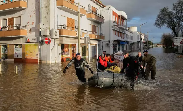 Police officers and marines evacuate residents from a hotel by inflatable boat along a flooded street after the Sado River overflowed following heavy rains in Alcácer do Sal, southern Portugal, Friday, Feb. 6, 2026. (AP Photo/Ana Brigida)