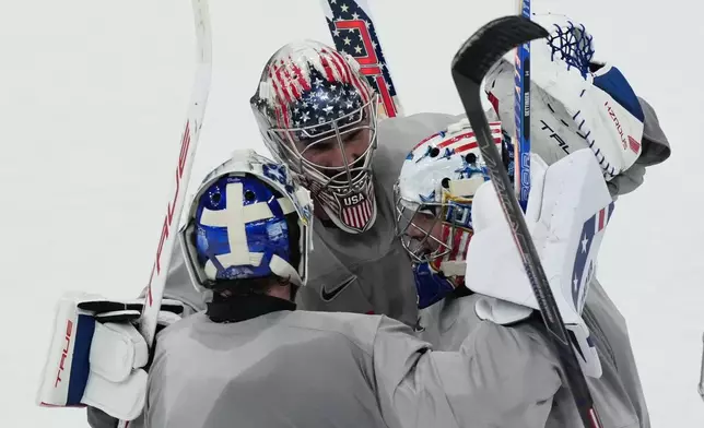 United States goalkeepers Connor Hellebuyck, Jake Oettinger, and Jeremy Swayman, gather on the ice during men's ice hockey practice at the 2026 Winter Olympics, in Milan, Italy, Sunday, Feb. 8, 2026. (AP Photo/Carolyn Kaster)