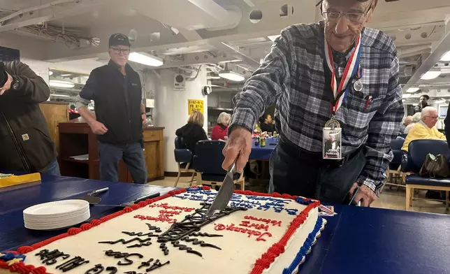 John "Johnny Q" Quinesso Sr, a WWII veteran, cuts a cake during his 100th birthday celebration on Thursday, Feb. 5, 2026 in Camden, N.J., aboard the Battleship New Jersey. (AP Photo/Tassanee Vejpongsa)