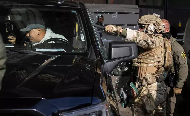 FILE - Federal immigration enforcement agents shatter a truck window and detain two men outside a Home Depot in Evanston, Ill., Dec. 17, 2025. (Ashlee Rezin/Chicago Sun-Times via AP, File)